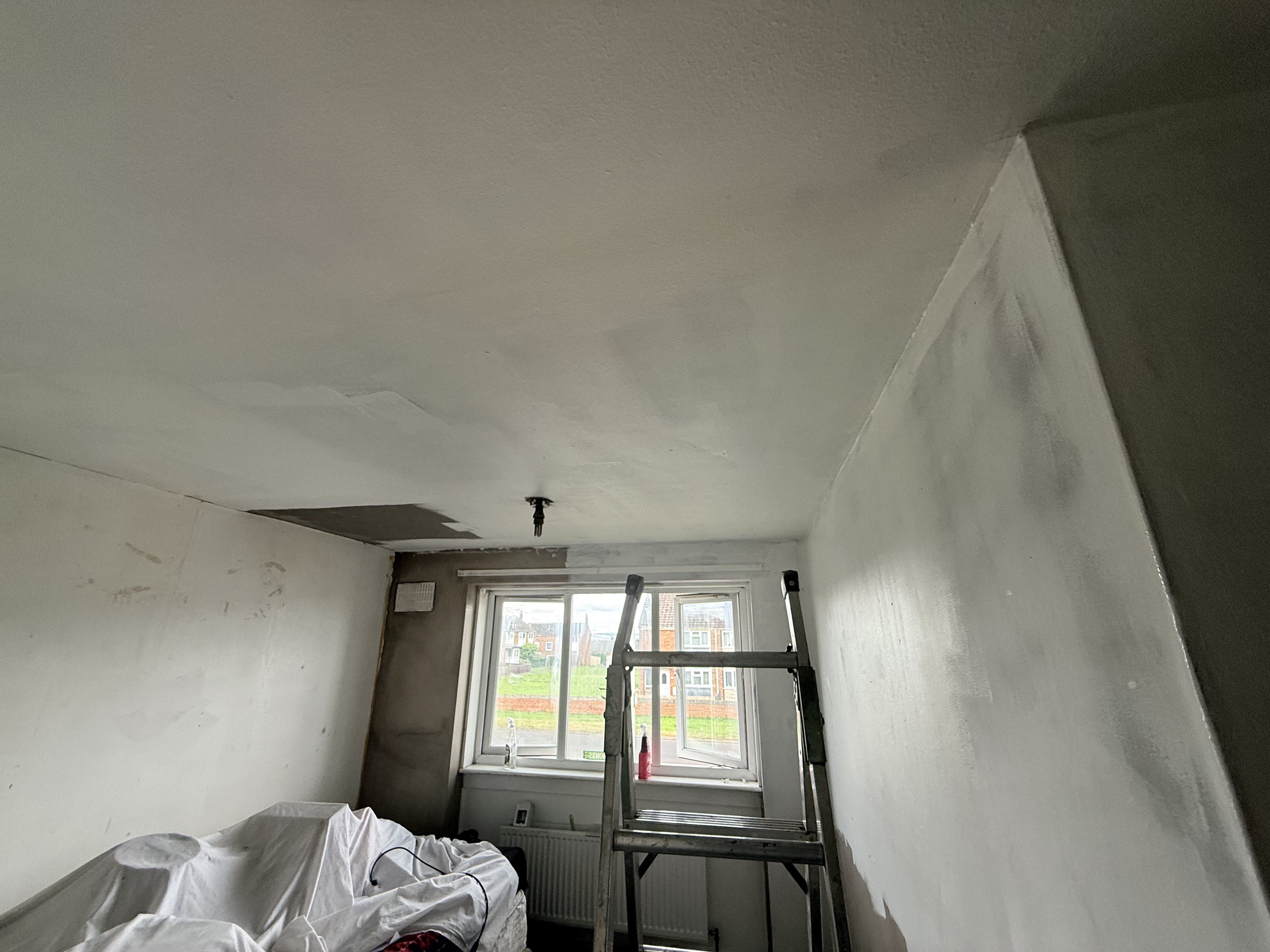 First white base coats flattening out across the fresh wall plaster