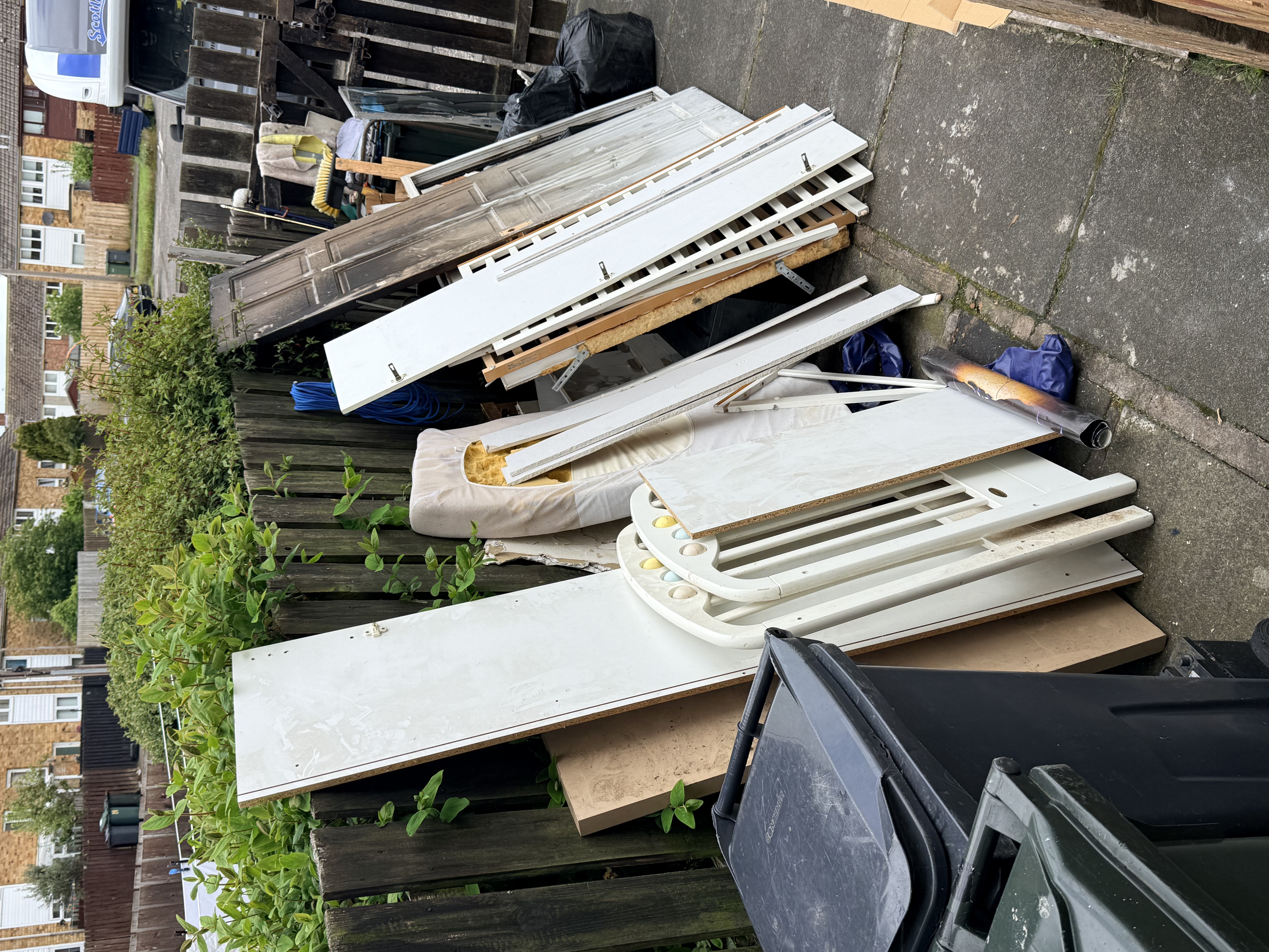 Old doors and white panels stacked by the fence